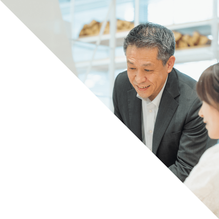 スーツ姿の男性が女性と向き合い、笑顔で対話する様子