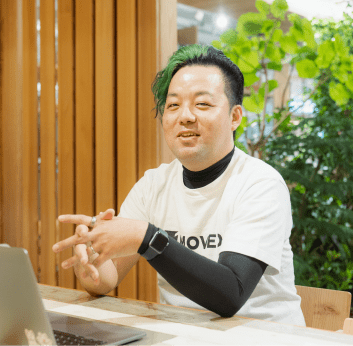 男性がノートパソコンの前で身振り手振りを交えながら話している様子