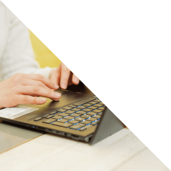 デスクでノートPCのキーボードをタイピングしている手元